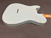Back of vintage white electric guitar body with wear and paint chipping, bolt-on maple neck visible, on gray background.