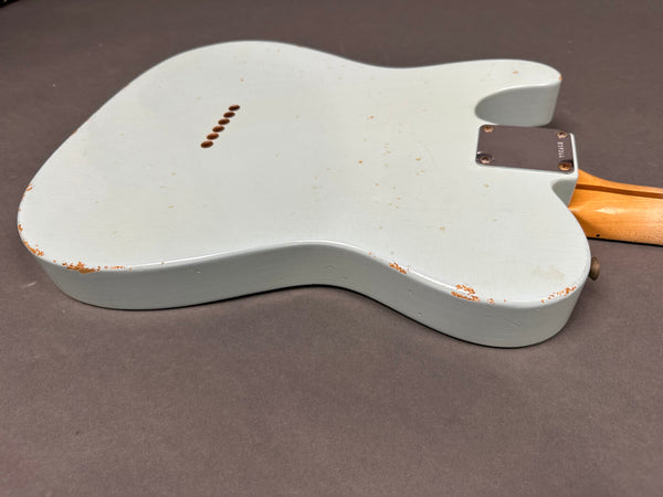 Back of white electric guitar body showing vintage wear and paint chipping, maple neck with metal neck plate and string ferrules on dark gray background
