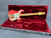 Red Burns electric guitar with maple neck and gold hardware in open black textured guitar case with red velvet interior lining
