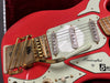 Close-up of red vintage electric guitar with gold Bigsby vibrato tailpiece, three single-coil pickups, white pickguard, and volume and tone control knobs, handcrafted by Burns London.