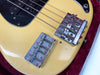 Close-up of vintage Fender bass guitar bridge and pickup on a yellow body with black pickguard in red velvet case