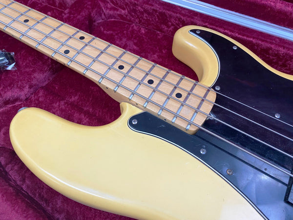Close-up of vintage cream electric bass guitar body and maple fretboard with black pickguard on red velvet case lining