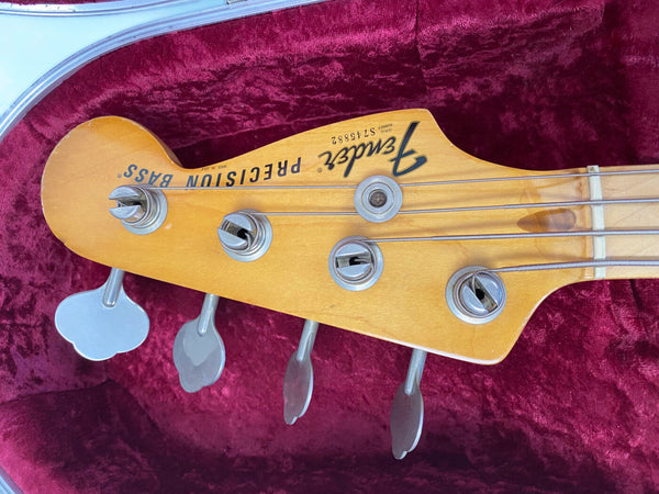 Fender Precision Bass headstock with vintage tuning pegs and natural wood finish in red plush guitar case.