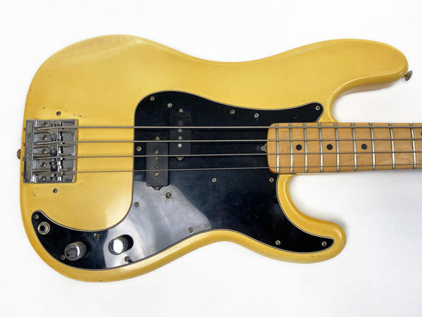 Vintage yellow electric bass guitar with black pickguard and maple fretboard, showing signs of wear and aging
