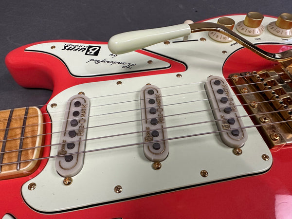 Close-up of red electric guitar with white pickguard, three single-coil BURNS RZE-O-MATIC pickups, volume and tone knobs, gold hardware, and vibrato arm.