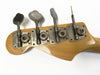 Close-up of vintage Fender bass guitar tuning pegs on natural wood headstock with metal gears and clamps