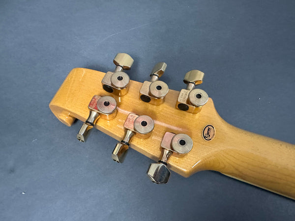 Close-up of vintage Burners guitar natural wood headstock with metal tuning pegs on gray background