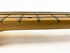 Close-up view of bass guitar fretboard with metal frets and four strings on light wood neck