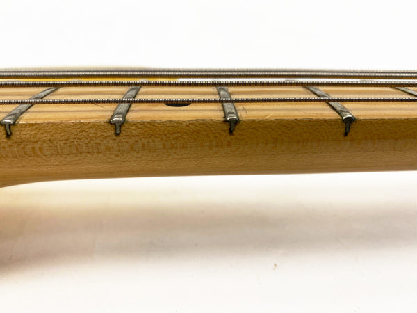 Close-up view of bass guitar fretboard with metal frets and four strings on light wood neck