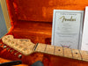 Fender 1956 Stratocaster NOS guitar headstock with gold tuning pegs in orange plush-lined guitar case with Fender certificate of authenticity