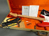 Fender Stratocaster guitar with red body and figured maple neck in orange plush-lined tweed hard case, including certificate of authenticity, pre-sales checklist, leather strap, tremolo arm, and Fender polishing cloth