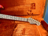 Fender Stratocaster guitar headstock and neck with birdseye maple fretboard in orange vintage-style hard guitar case interior