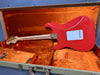 Red electric guitar with quilted maple neck in open tweed hard case with orange plush interior, back view