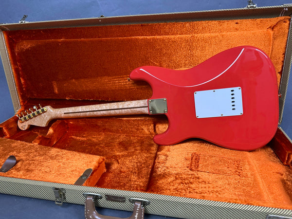 Red electric guitar with quilted maple neck in open tweed hard case with orange plush interior, back view