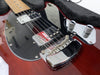 Close-up of red electric guitar body with chrome bridge, pickups, and control knobs, wooden neck, and black pickguard in guitar case interior.
