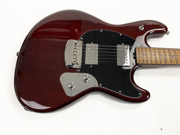 Close-up of dark red electric guitar body with black pickguard, chrome bridge cover, two chrome humbucker pickups, and maple neck with dot inlays on white background