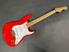 Red Fender electric guitar with white pickguard and maple neck with birdseye maple fretboard on gray background