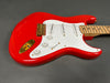 Red electric guitar with white pickguard, gold hardware, and maple neck on gray background