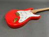 Red electric guitar with white pickguard, maple neck, and gold hardware on gray background