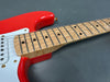 Close-up of red electric guitar with white pickguard and maple neck featuring birdseye maple fretboard and dot inlays on gray background