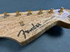 Close-up of Fender Stratocaster guitar headstock with synchronized tremolo and gold tuning pegs on birdseye maple wood finish