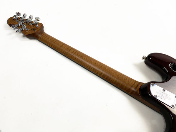 Back side view of electric guitar neck showing figured wood grain maple neck with chrome tuning pegs and dark red guitar body on a white background
