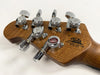 Close-up of guitar headstock with chrome tuning pegs and California Heritage logo on natural wood grain finish