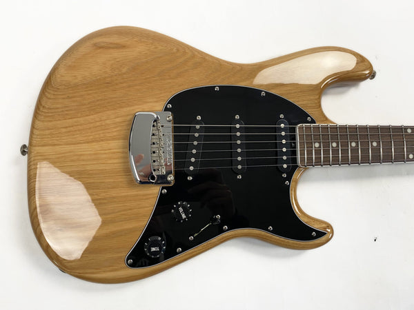 Natural finish electric guitar body with black pickguard, three single-coil pickups, and chrome bridge, rosewood fretboard close-up on white background