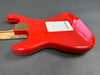 Red electric guitar body with white backplate and natural wood neck on gray background