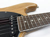 Close-up of electric guitar fretboard and black pickup on natural wood body with chrome frets and white dot inlays