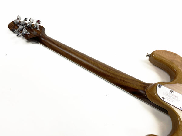 Back view of Music Man electric guitar neck and headstock showing chrome tuning pegs and natural wood finish