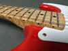 Close-up of electric guitar neck with quilted maple fretboard, black dot inlays, and red body with white pickguard and gold screws