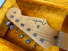 Close-up of Fender Stratocaster electric guitar headstock with tuning pegs in vintage yellow plush guitar case