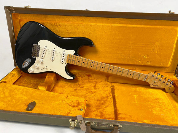 Black Fender Stratocaster electric guitar with maple neck and white pickguard in vintage orange Fender hard case