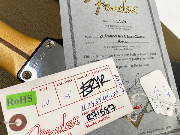 Close-up of Fender 57 Stratocaster Closet Classic certificate of authenticity and inspection tags with serial number R71587 on guitar neck plate and paperwork