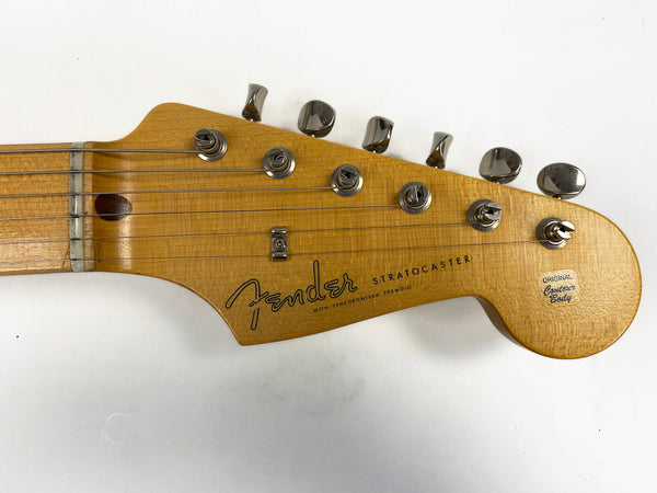 Close-up of Fender Stratocaster guitar headstock with original tuners and logo on natural wood finish against white background