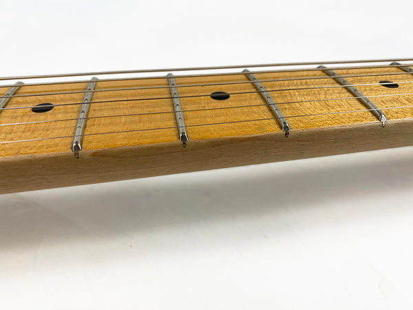 Close-up of maple guitar neck with metal frets and dot inlays on the fretboard, steel guitar strings, white background