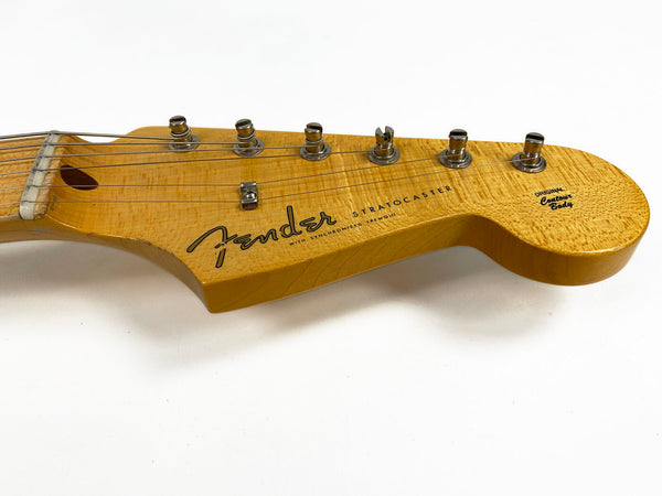 Close-up of natural wood Fender Stratocaster headstock with six tuning pegs and strings, showing "Original Contour Body" text and vintage-style logo on white background