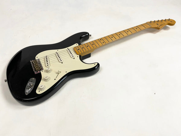 Black Fender Stratocaster electric guitar with maple neck and white pickguard on white background