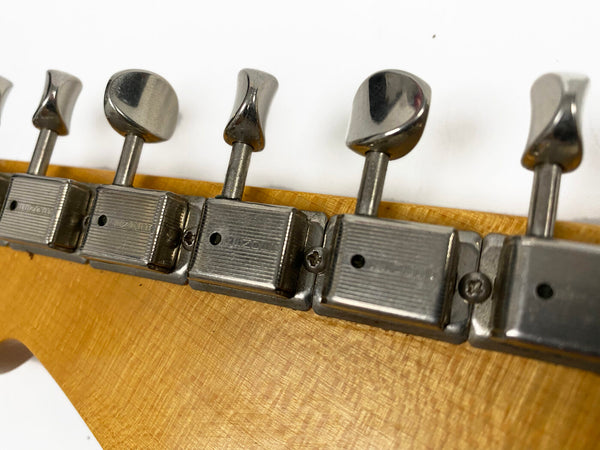 Close-up of vintage metal guitar tuning pegs on a wooden guitar headstock with a light finish, showing the brand name "Mizone" on the tuners.