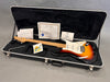 G&L electric guitar with sunburst finish in hard case with certificate of authenticity, warranty papers, and tremolo arm.