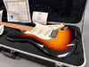 G&L electric guitar in sunburst finish resting in black plush-lined hard case with certificate of authenticity and warranty card visible