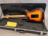 Electric guitar with sunburst finish and maple neck resting in black plush-lined hard case with yellow cleaning cloth inside case