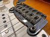 Close-up of electric guitar bridge and strings on sunburst finish with white pickup and volume knob visible
