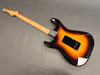 Electric guitar with sunburst finish body and maple neck, back view showing neck plate and tremolo cavity cover on gray background