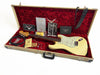 Fender vintage-style cream electric guitar in open beige hardshell case with red plush interior, including Fender owner's manual, certificate of authenticity, guitar strap, instrument cable, and assorted accessories.