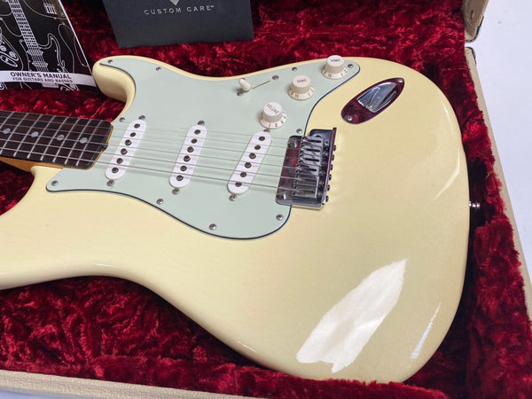 Vintage cream electric guitar with three single-coil pickups and white control knobs in red velvet-lined hard case