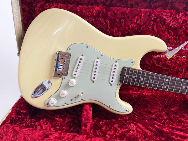Vintage cream electric guitar with white pickguard and three single-coil pickups resting in red velvet-lined case