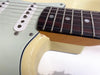 Close-up of vintage electric guitar neck joint with visible paint chip and aged cream finish, rosewood fretboard, and single-coil pickups