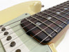 Close-up of electric guitar strings, rosewood fretboard, and single-coil pickups on cream-colored body